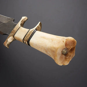 Decorative knife with bone handle and gold accents on a dark background